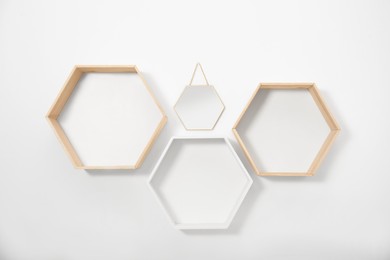 Photo of Empty honeycomb shaped shelves and small mirror on white wall