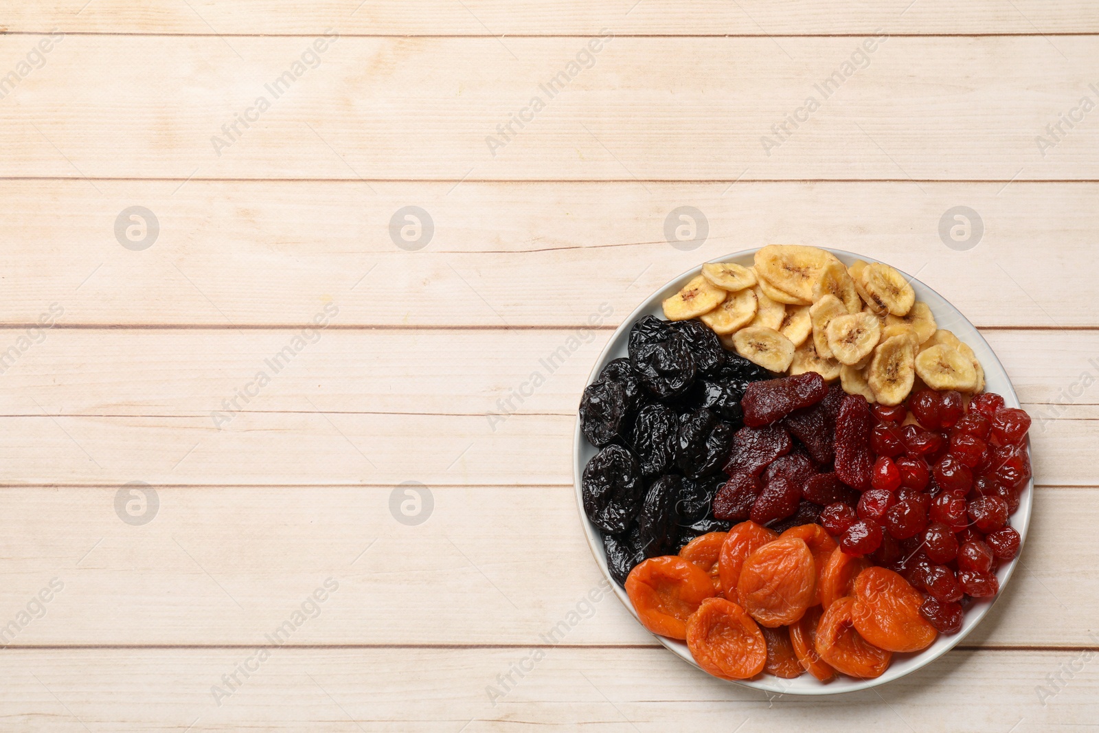 Photo of Delicious dried fruits on white wooden table, top view. Space for text