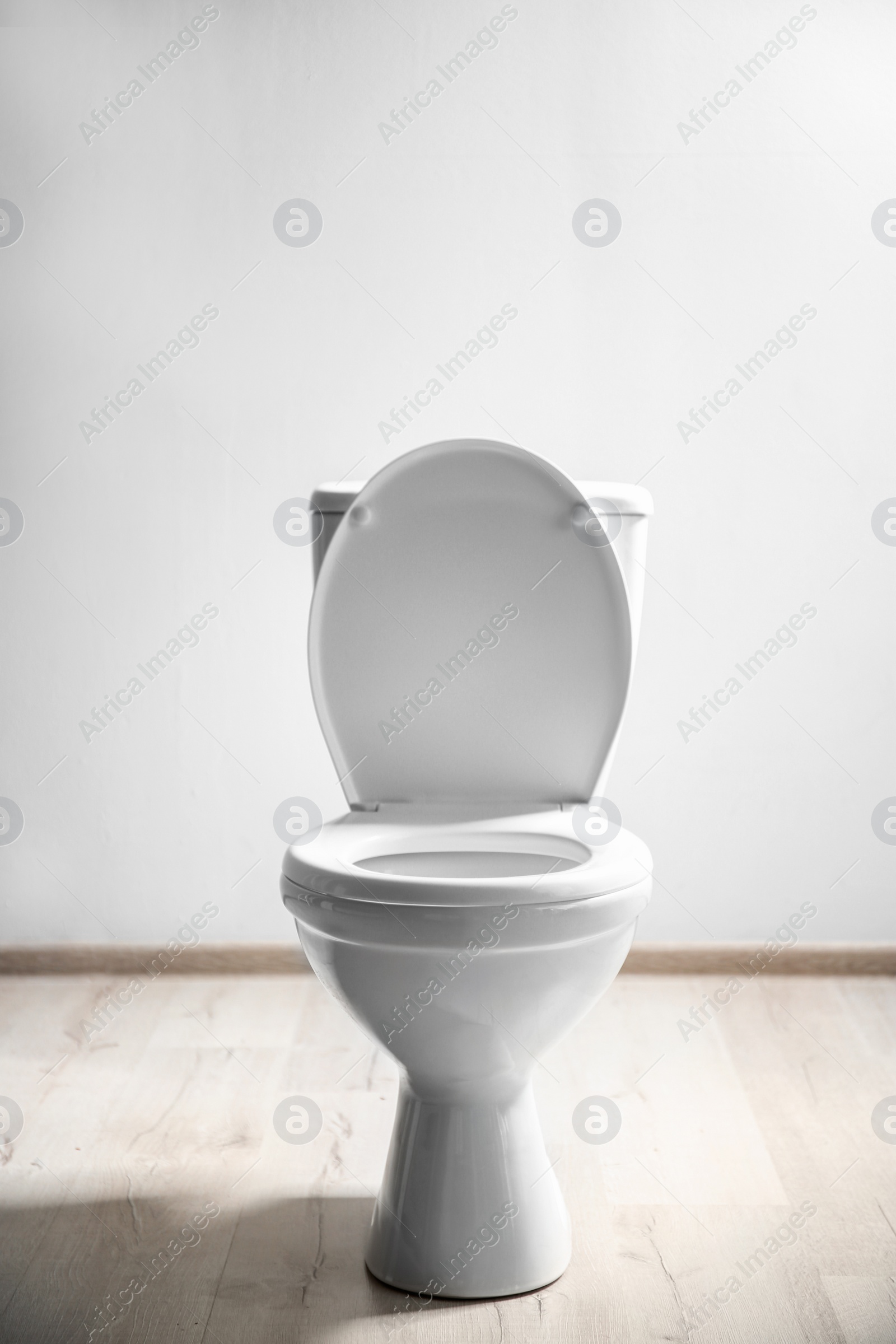 Photo of New ceramic toilet bowl near light wall