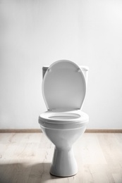 New ceramic toilet bowl near light wall