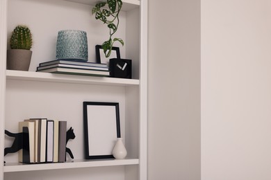 Photo of Interior design. Shelves with stylish accessories, potted plant and books indoors. Space for text