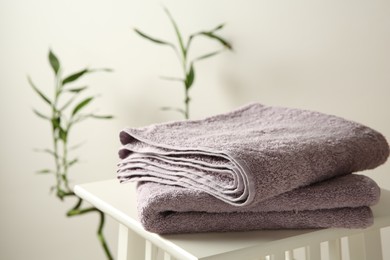 Photo of Violet towels on stool against white wall, closeup