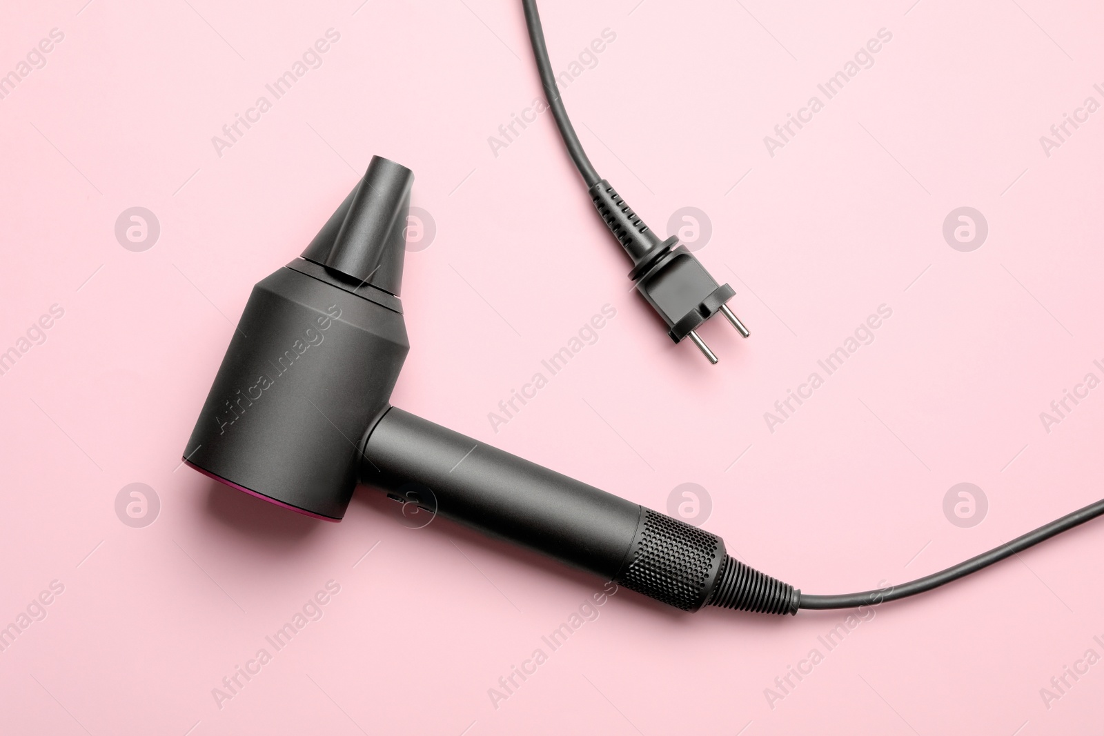 Photo of Hair dryer on pink background, top view. Professional hairdresser tool