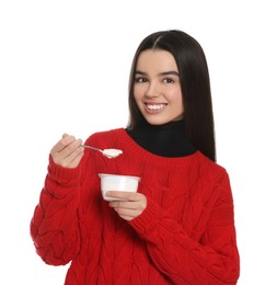 Happy teenage girl with delicious yogurt and spoon on white background
