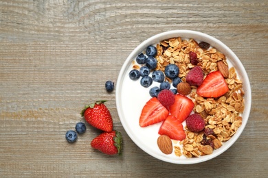 Photo of Tasty homemade granola served on wooden table, flat lay. Healthy breakfast