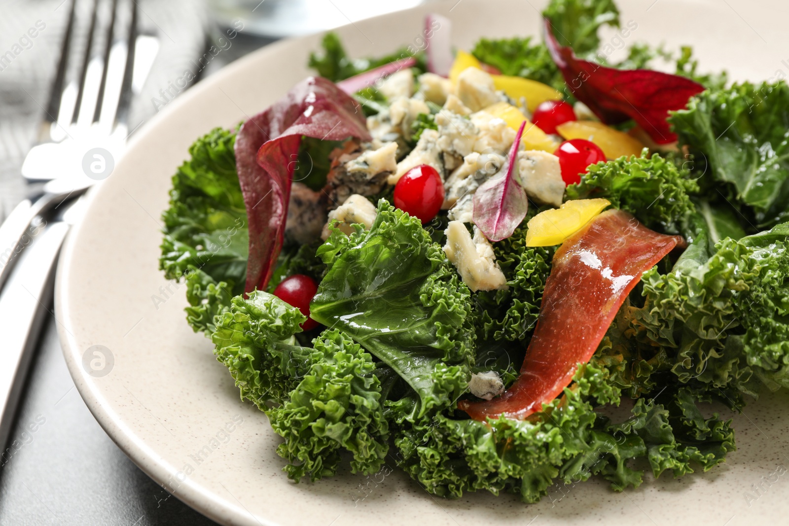 Photo of Tasty fresh kale salad on grey table, closeup