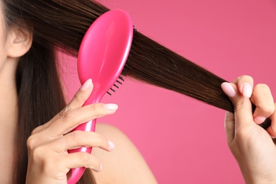 Photo of Woman with hair brush on color background, closeup