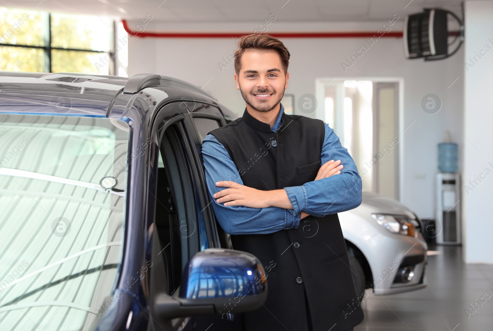 Photo of Young man near new car in dealership