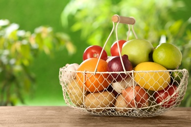 Photo of Basket full of fresh vegetables and fruits on table outdoors, space for text