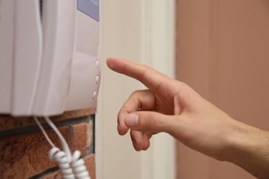 Photo of Man pressing button on intercom panel indoors, closeup