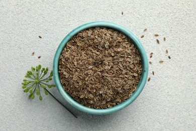 Photo of Bowl of dry seeds and fresh dill on grey table, flat lay