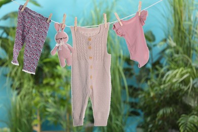 Baby clothes and bunny toy drying on laundry line outdoors