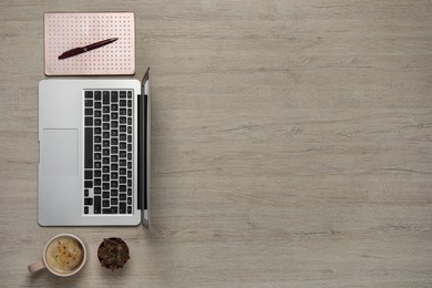 Photo of Modern laptop, houseplant, notebook and cup of coffee on wooden table, flat lay. Space for text