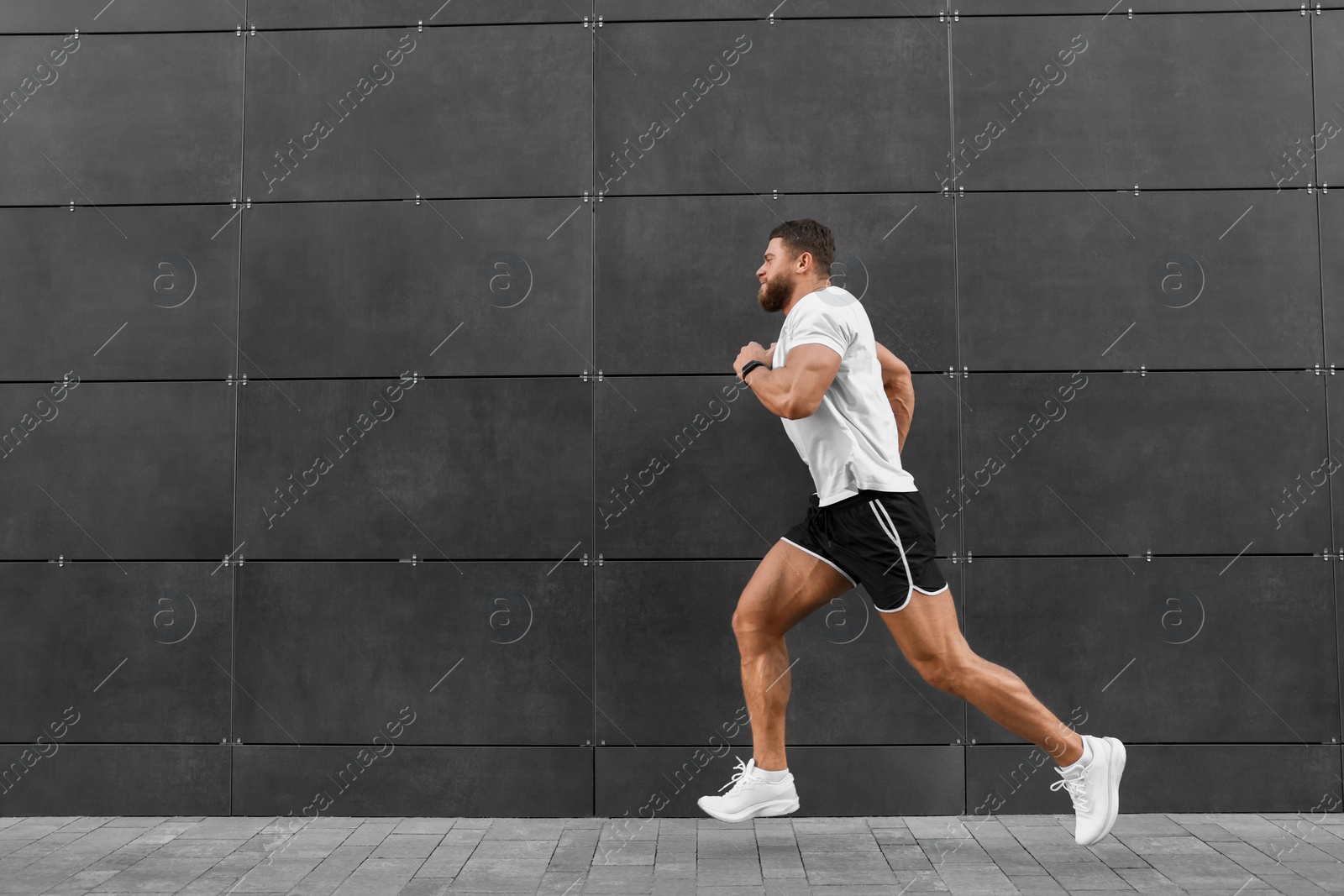 Photo of Young man running near building outdoors. Space for text