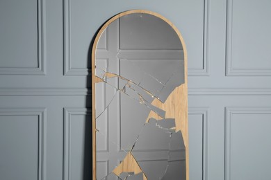 Photo of Broken mirror with many cracks near grey wall