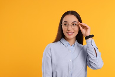 Beautiful woman wearing glasses on orange background, space for text