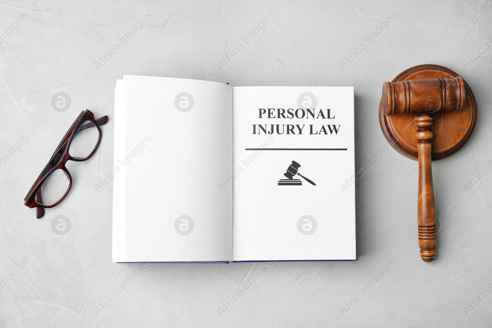 Photo of Book with words PERSONAL INJURY LAW, gavel and glasses on grey background, top view