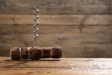 One corkscrew on wooden table, closeup. Space for text