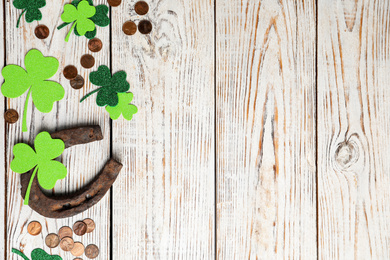 Photo of Flat lay composition with horseshoe on white wooden background, space for text. St. Patrick's Day celebration