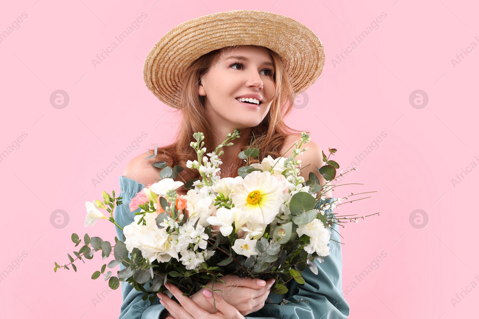 Photo of Beautiful woman in straw hat with bouquet of flowers on pink background