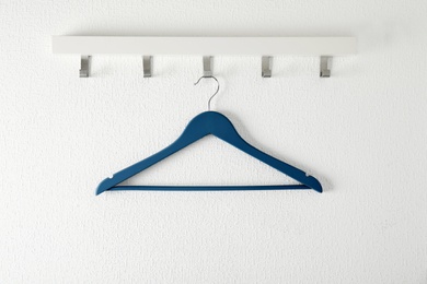 Photo of Rack with empty clothes hanger on light wall. Wardrobe accessory