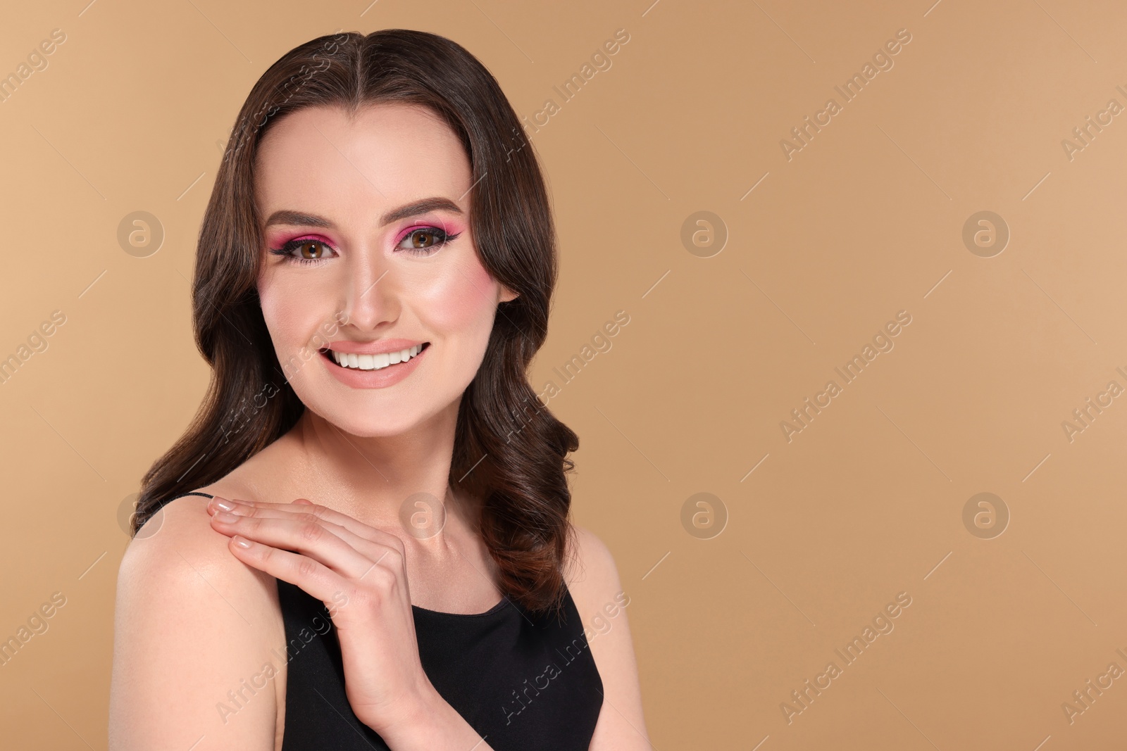 Photo of Portrait of beautiful young woman with makeup and gorgeous hair styling on beige background. Space for text
