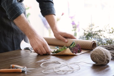 Male florist creating beautiful bouquet at table, closeup