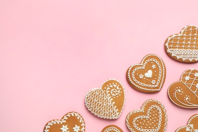 Gingerbread hearts decorated with icing on pink background, flat lay. Space for text