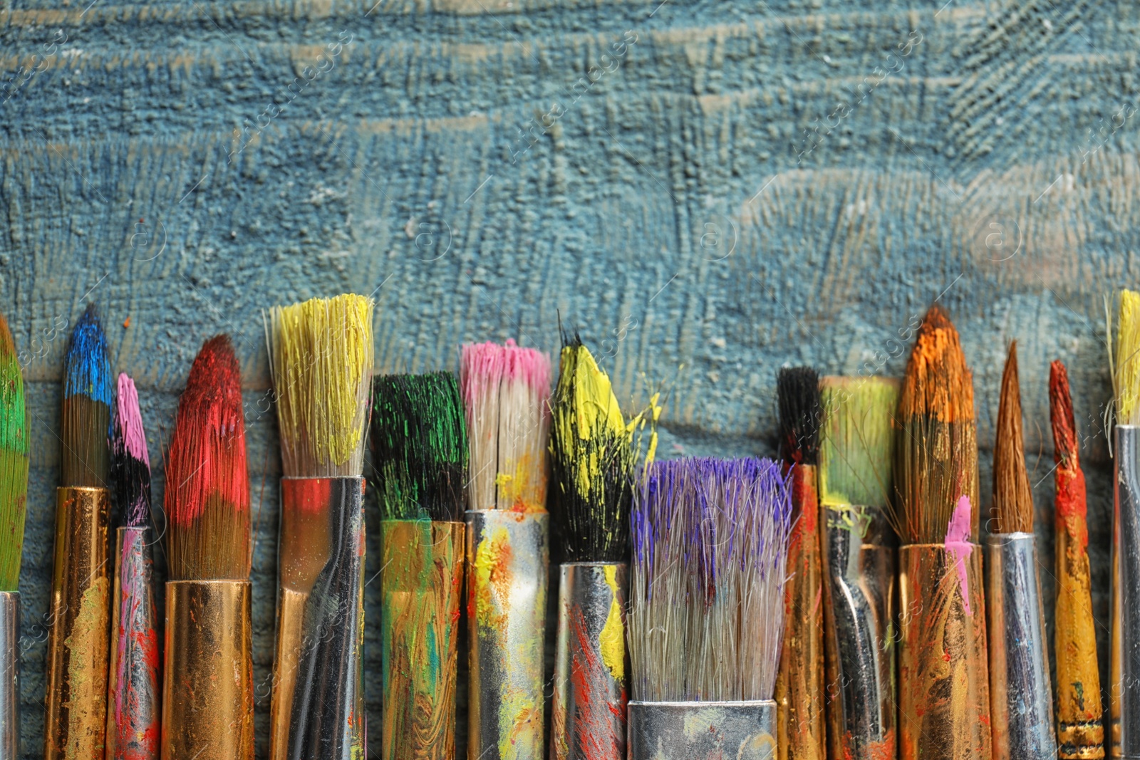 Photo of Different paint brushes on wooden background, top view with space for text