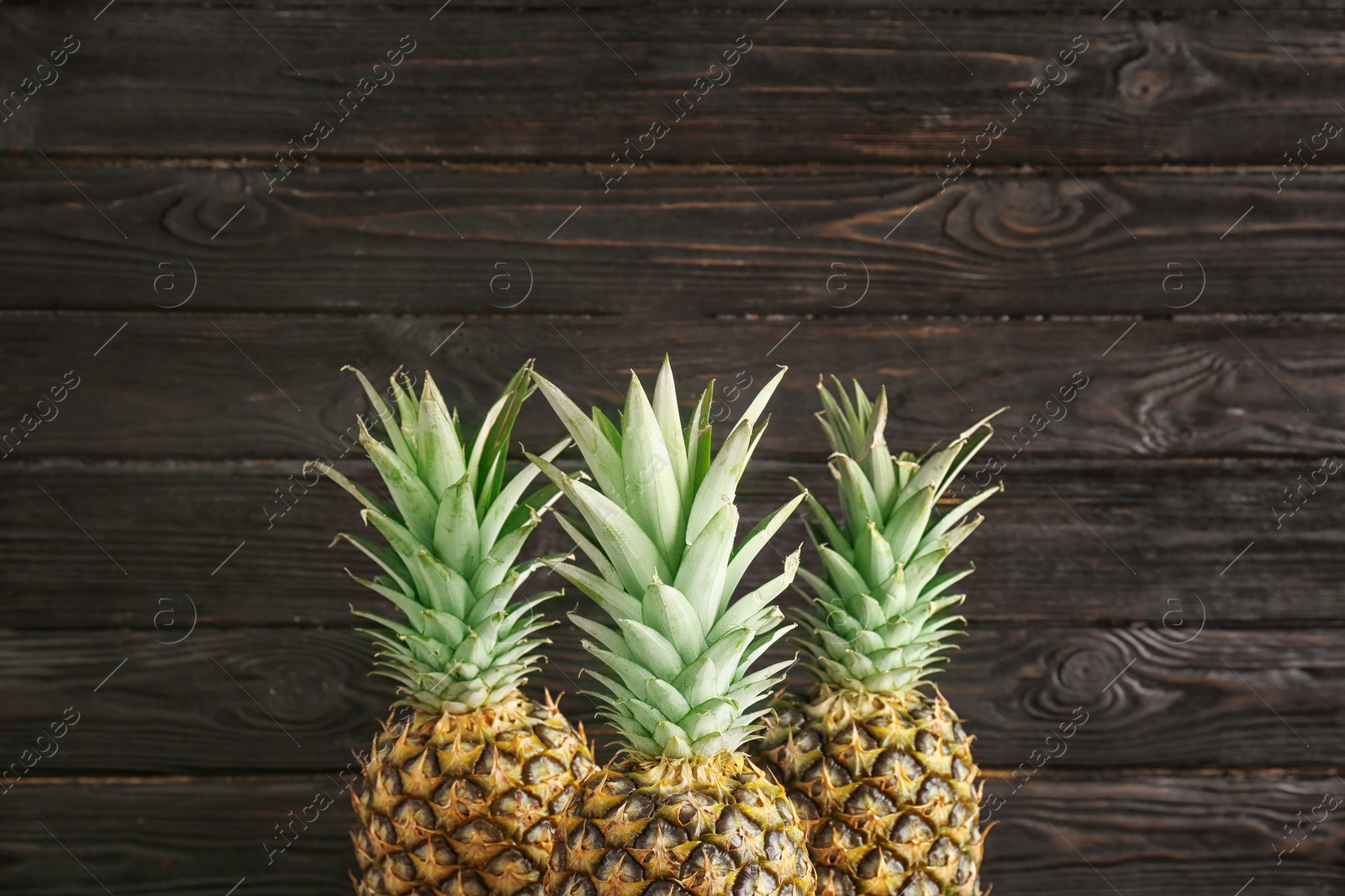 Photo of Fresh pineapples on wooden background