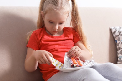 Photo of Little child with plate of different pills at home. Household danger