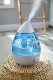 Photo of Modern air humidifier on wicker pouf indoors