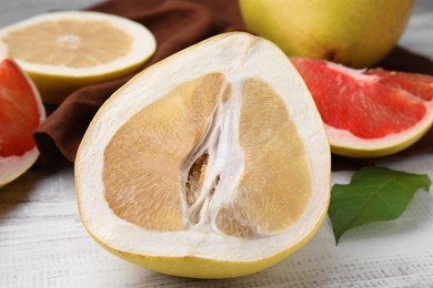 Different sorts of tasty pomelo fruits on white wooden table, closeup