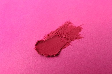Photo of Smear of beautiful lipstick on pink background, top view