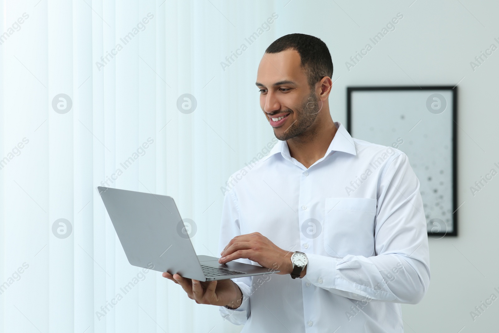 Photo of Handsome young man with laptop at home