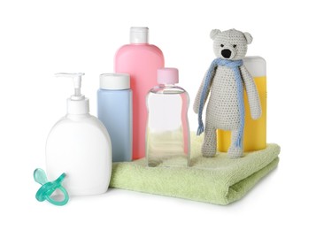 Bottles of baby cosmetic products, towel, pacifier and toy bear on white background