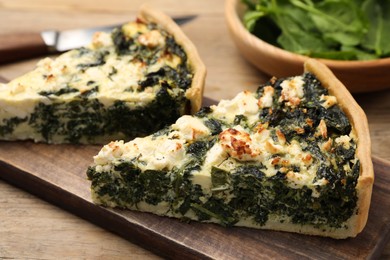 Pieces of delicious homemade spinach quiche on wooden table, closeup