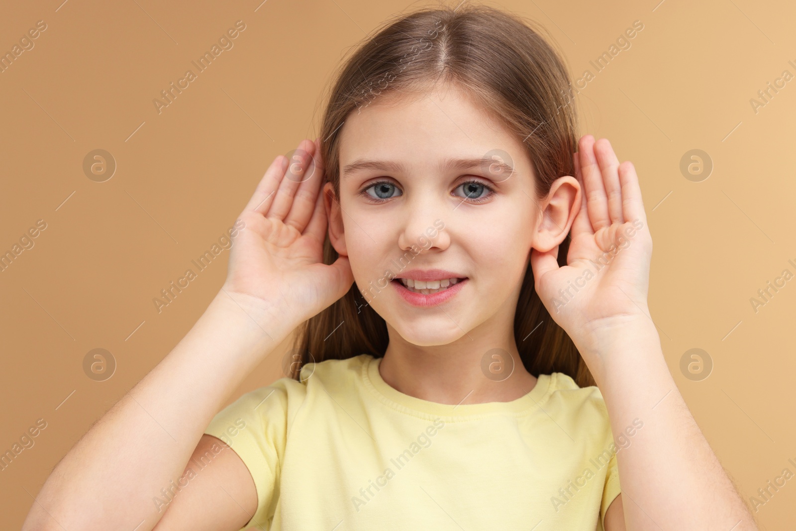 Photo of Little girl with hearing problem on pale brown background