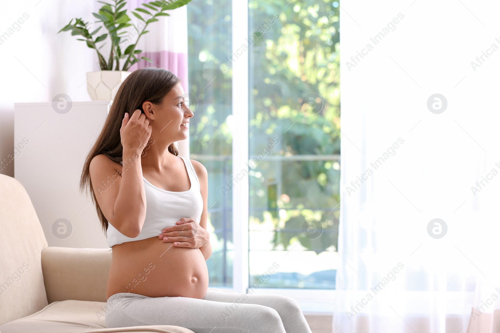 Photo of Pregnant woman sitting on sofa at home