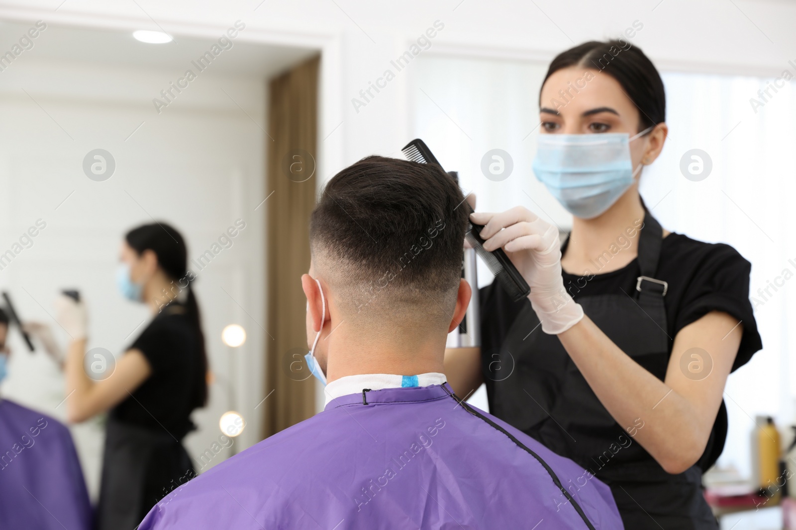 Photo of Professional stylist working with client in salon. Hairdressing services during Coronavirus quarantine