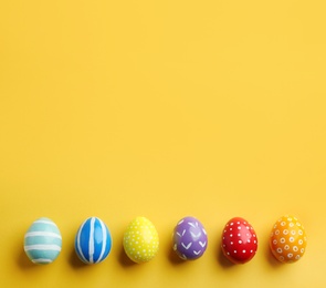 Photo of Flat lay composition of painted Easter eggs on color background, space for text