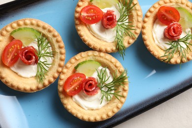 Delicious canapes with dry smoked sausages, cream cheese and vegetables on light table, flat lay