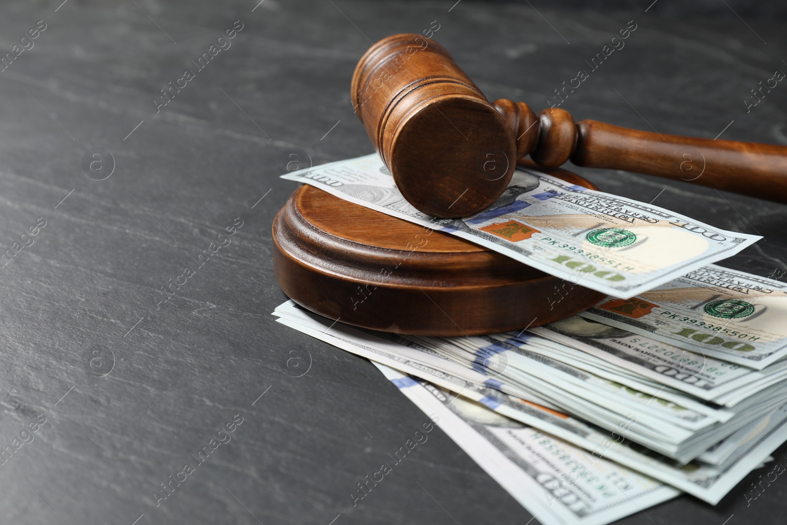 Photo of Judge's gavel and money on dark grey table, closeup. Space for text