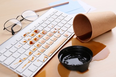 Photo of Cup of coffee spilled over computer keyboard on wooden office desk