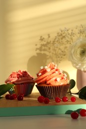 Photo of Delicious cupcake with bright cream and flowers on white wooden table