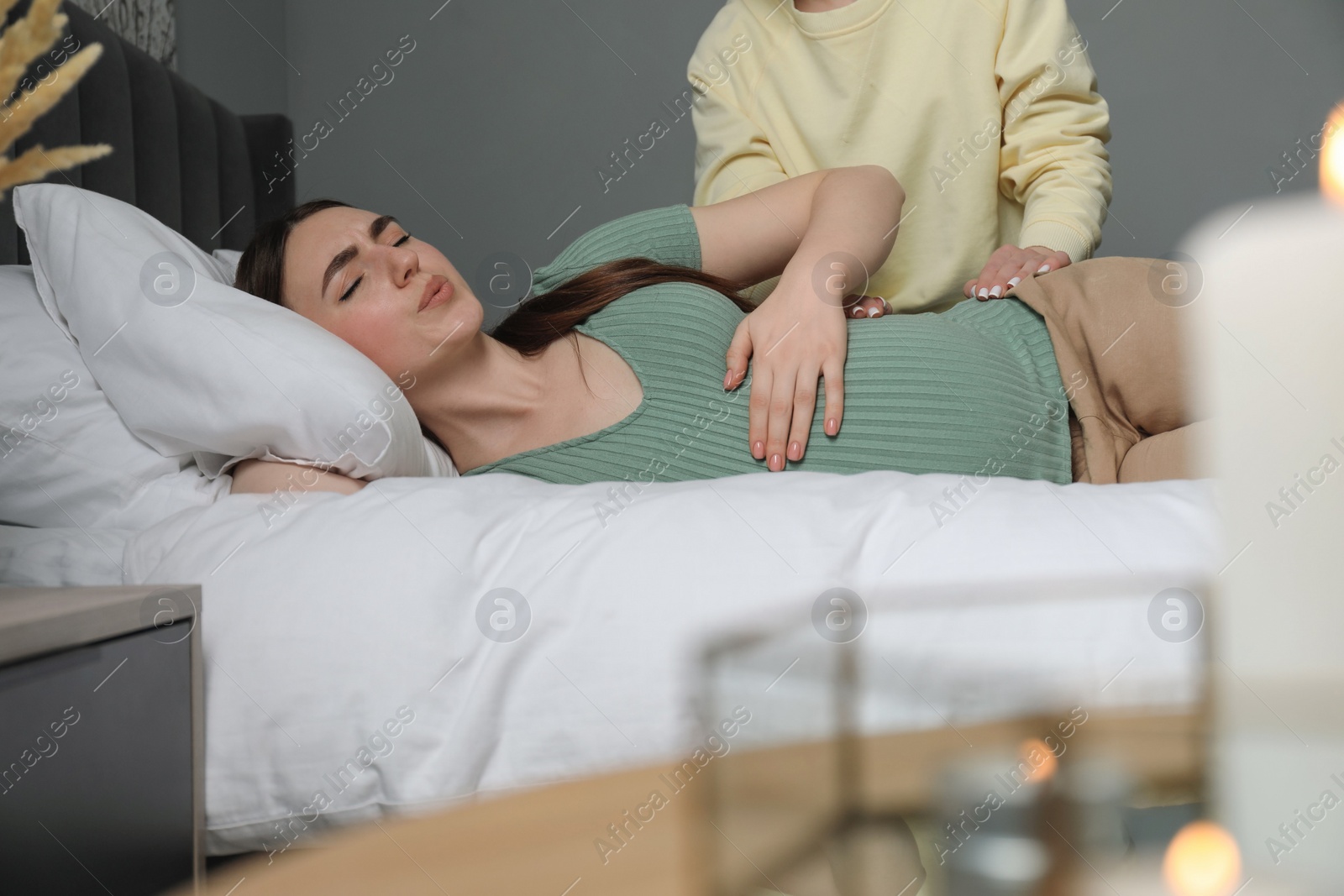 Photo of Doula taking care of pregnant woman in bedroom. Preparation for child birth