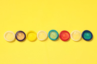 Condoms on yellow background, top view. Safe sex