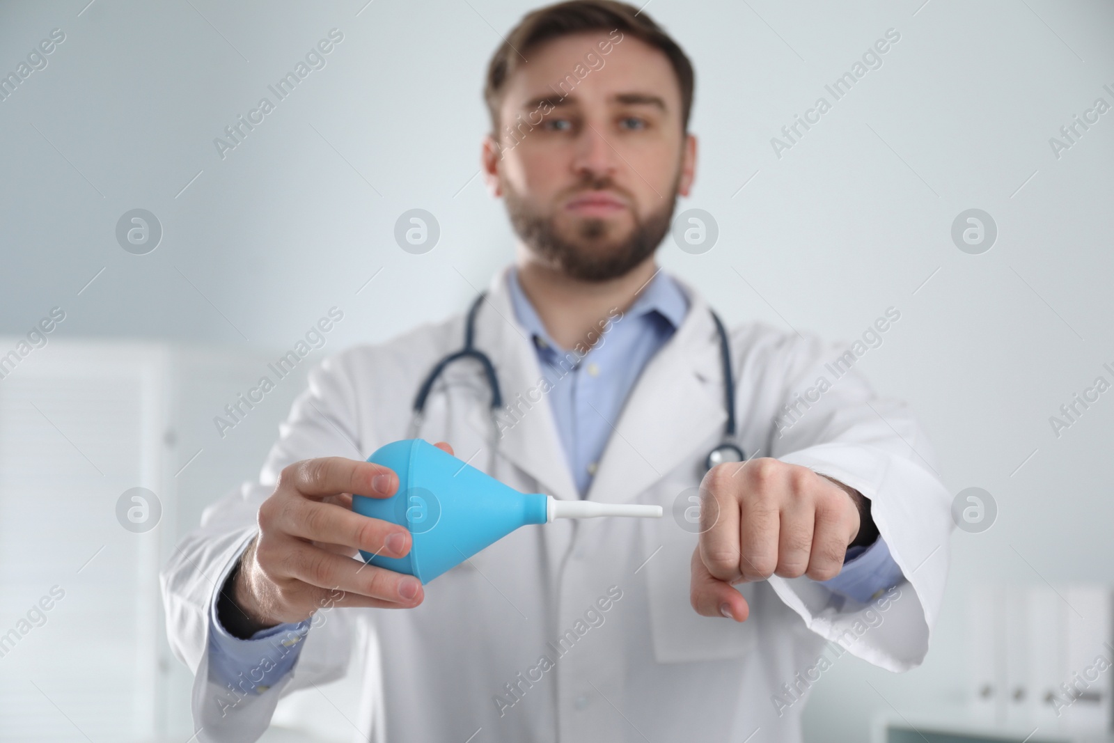 Photo of Doctor demonstrating usage of enema in examination room, focus on hands