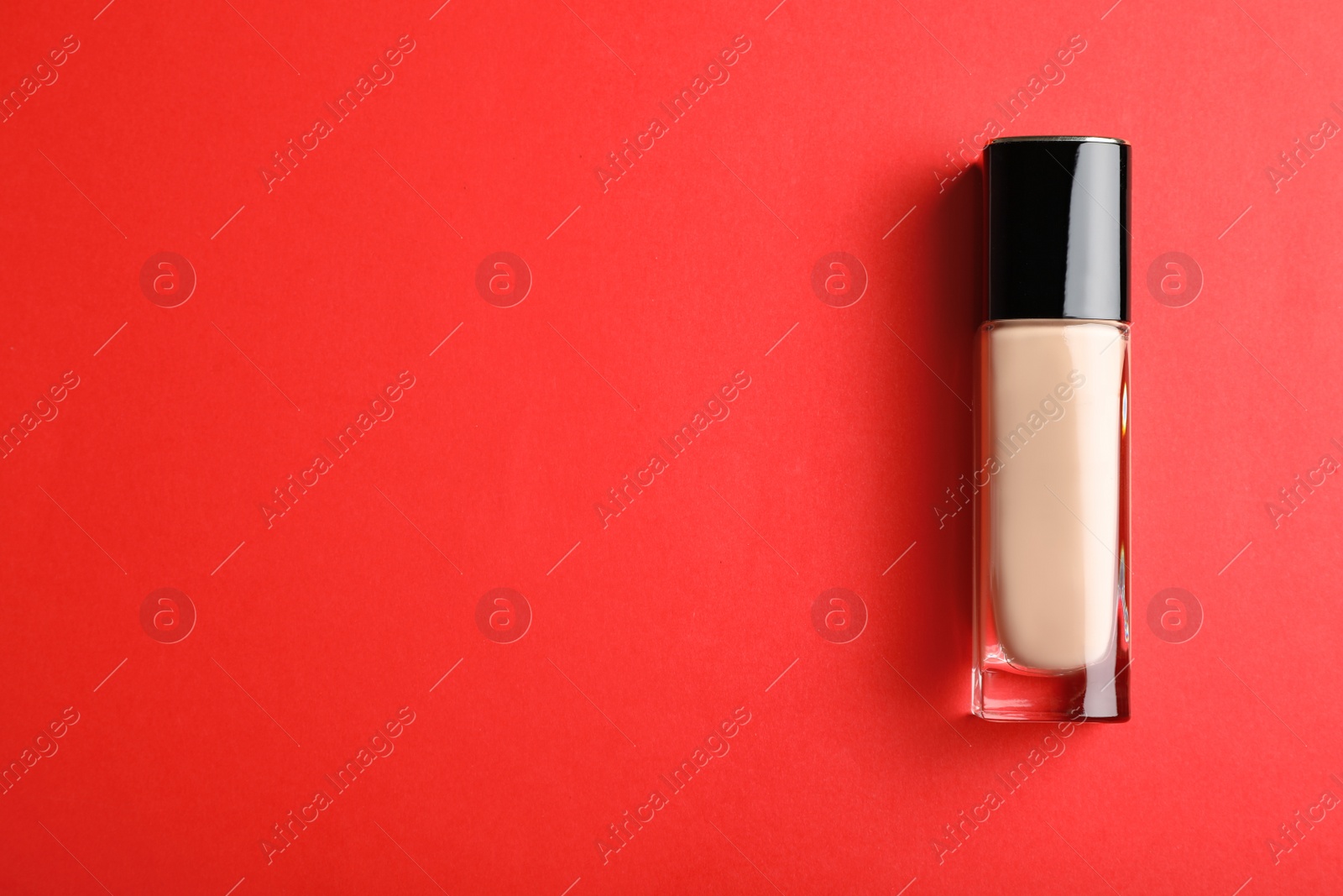 Photo of Bottle of skin foundation and space for text on color background, top view