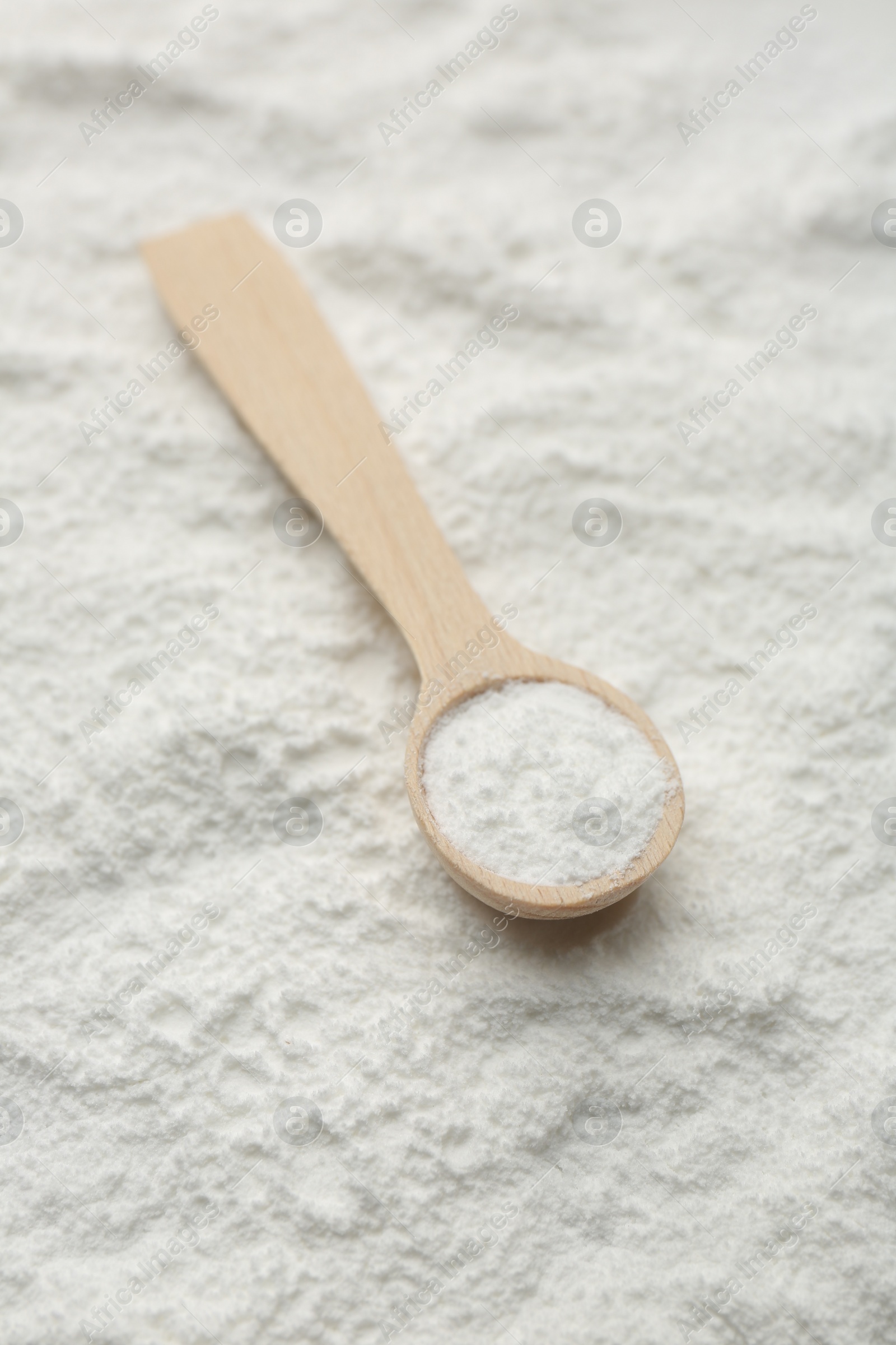 Photo of One wooden spoon on baking powder, closeup